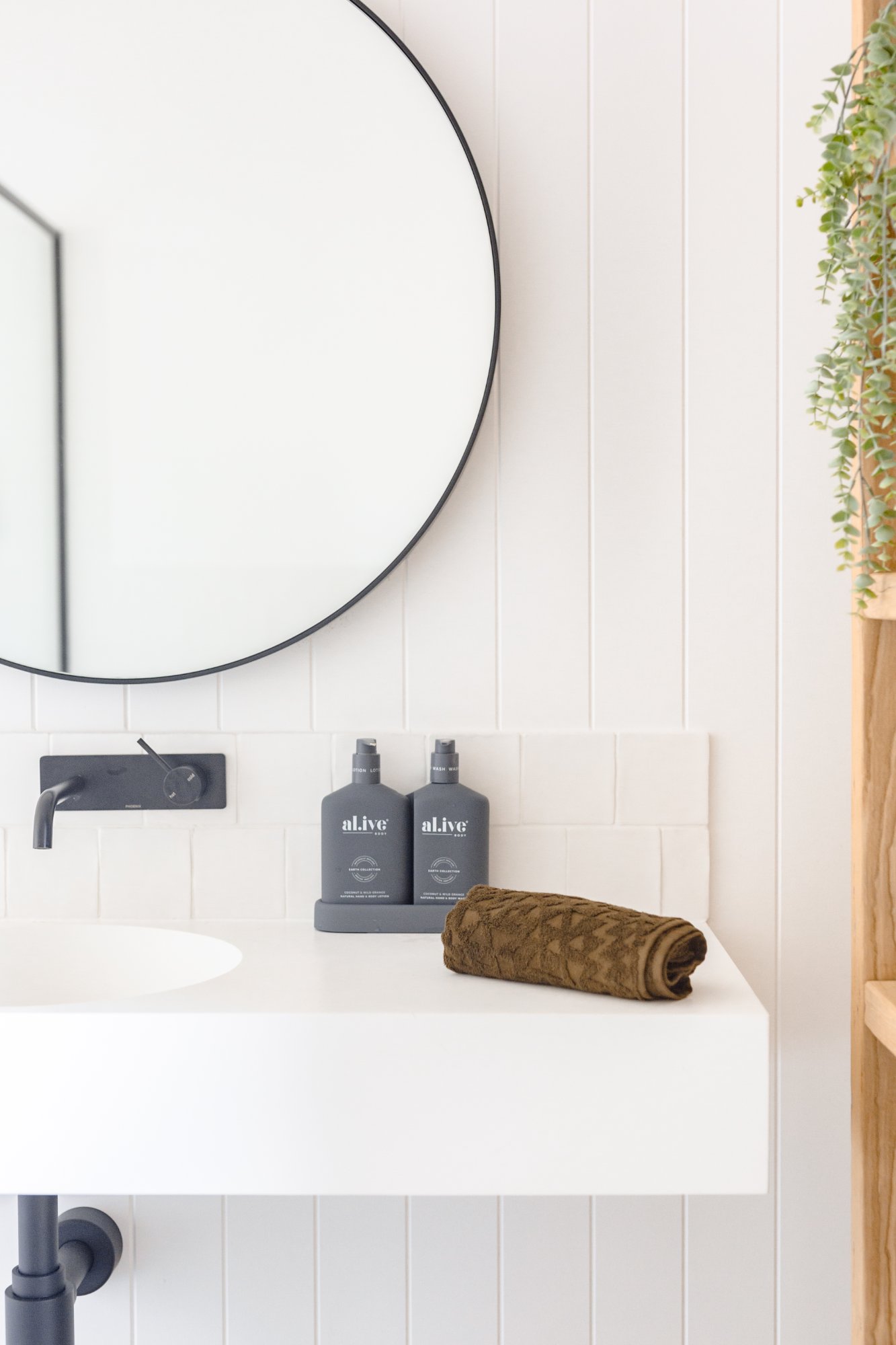 Bathroom vanity detail with round black-framed mirror and premium amenities
