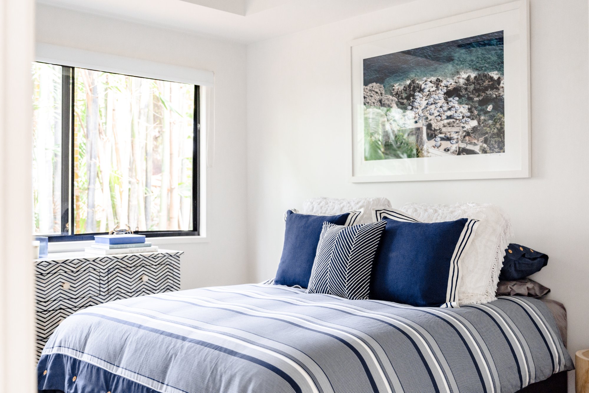 Bedroom 2 with navy blue coastal bedding, garden views and framed ocean artwork