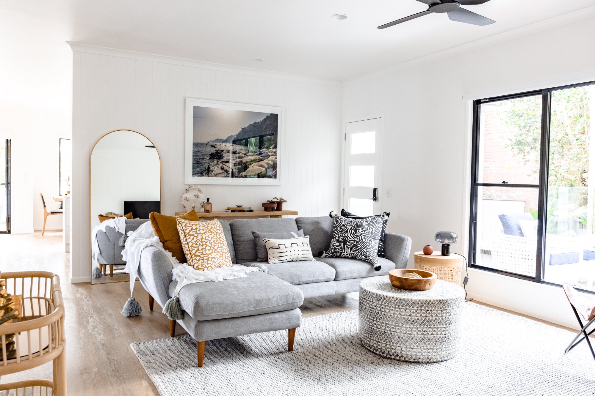Bright open-plan living room with grey sofa and coastal artwork at LUXE Noosa Heads